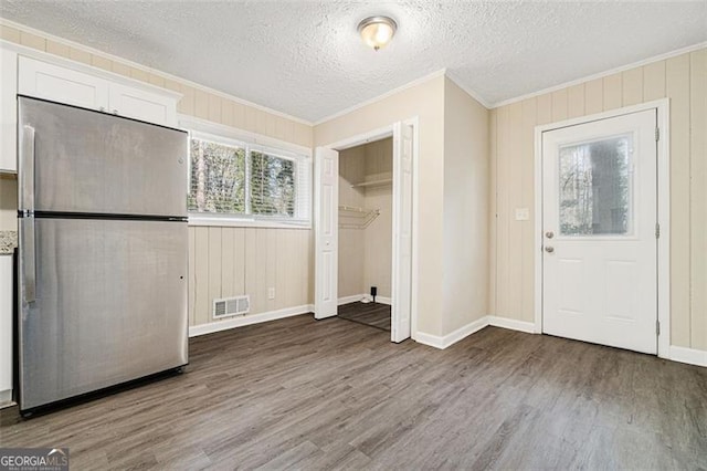 foyer with a textured ceiling, crown molding, and dark wood-type flooring