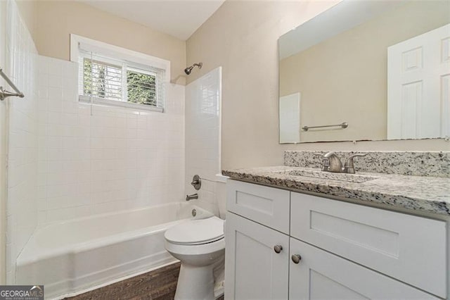 full bathroom with hardwood / wood-style floors, toilet, vanity, and tiled shower / bath