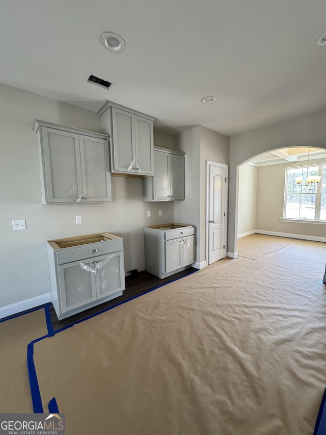 kitchen with arched walkways, recessed lighting, gray cabinets, visible vents, and baseboards