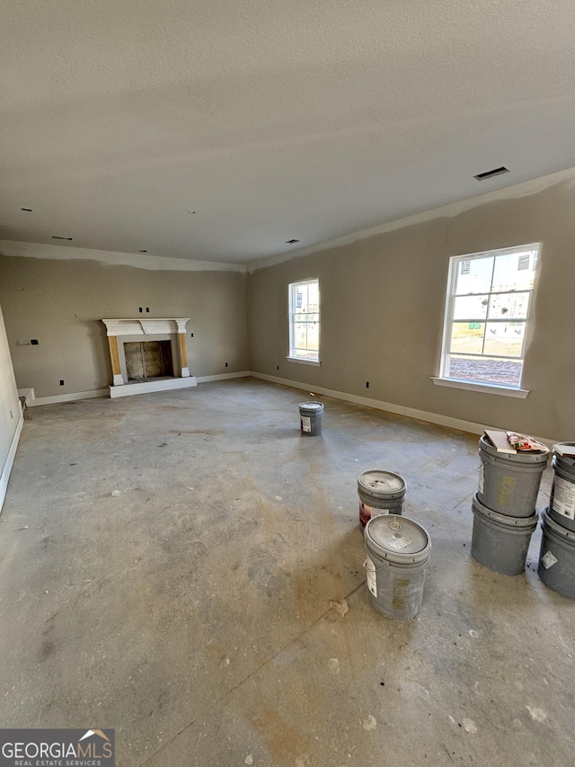 unfurnished living room with baseboards, visible vents, crown molding, a textured ceiling, and a fireplace