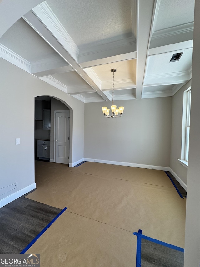 unfurnished dining area featuring baseboards, arched walkways, coffered ceiling, and a notable chandelier