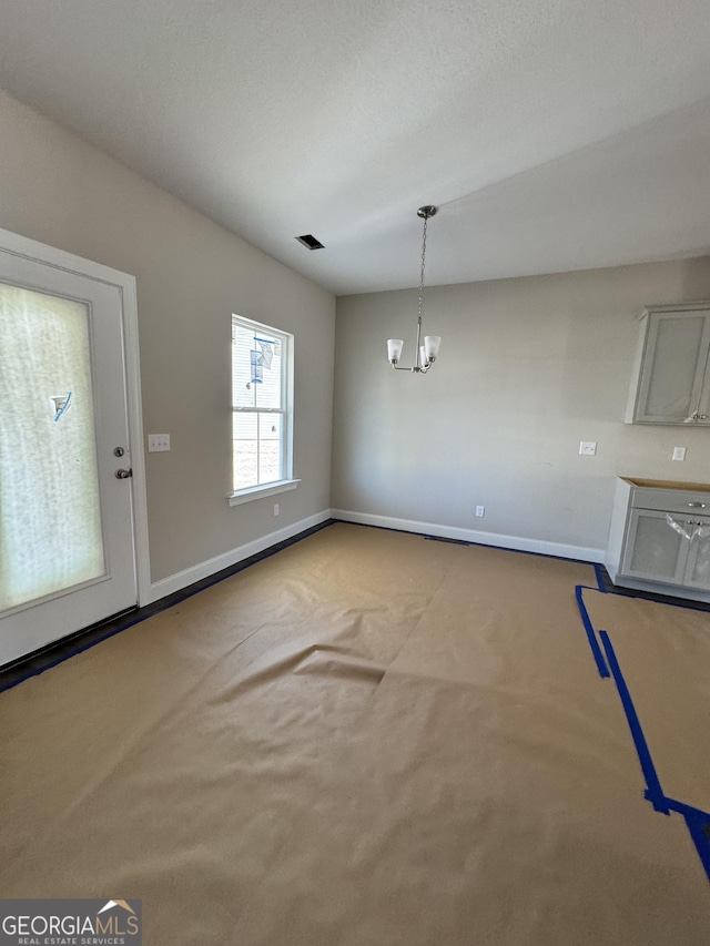 unfurnished dining area featuring carpet, visible vents, a notable chandelier, and baseboards