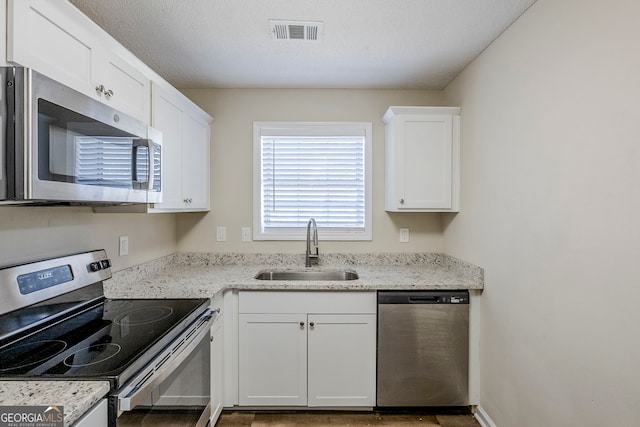 kitchen with sink, stainless steel appliances, white cabinets, and light stone counters