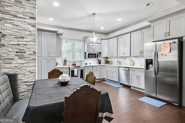 kitchen featuring decorative light fixtures, stainless steel appliances, ornamental molding, and decorative backsplash