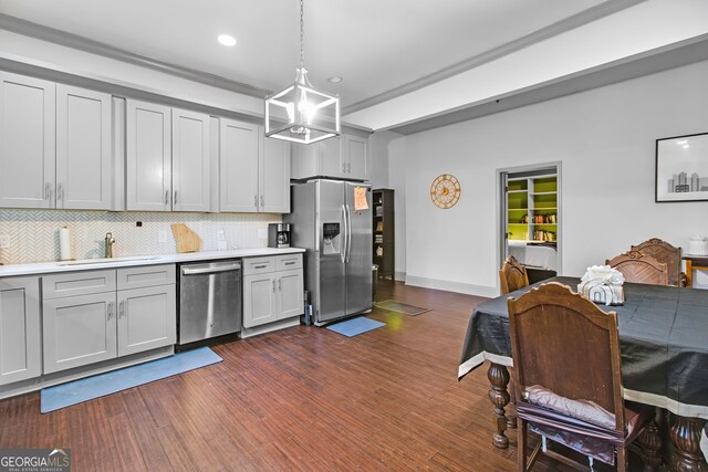 kitchen with stainless steel appliances, sink, decorative light fixtures, backsplash, and dark wood-type flooring