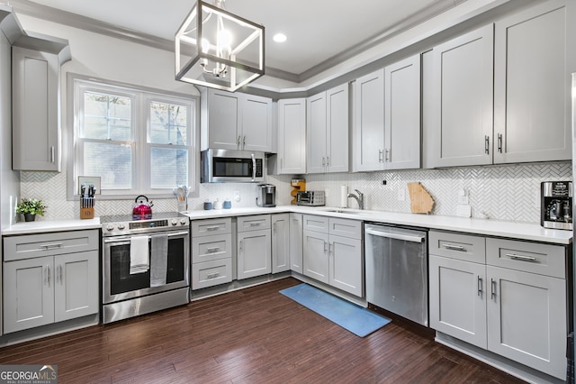 kitchen with appliances with stainless steel finishes, gray cabinetry, decorative light fixtures, and tasteful backsplash