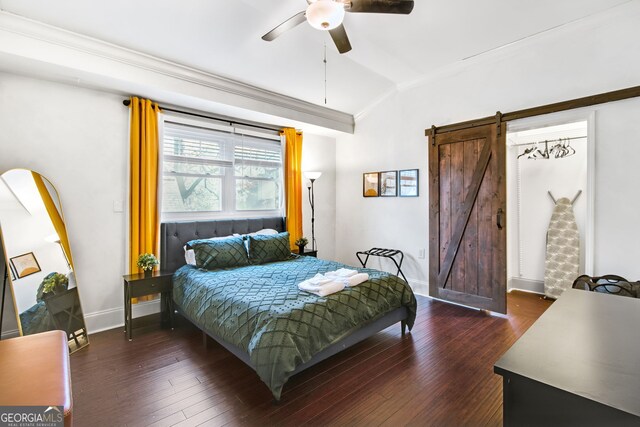 bedroom with vaulted ceiling, ceiling fan, a barn door, dark hardwood / wood-style flooring, and ornamental molding