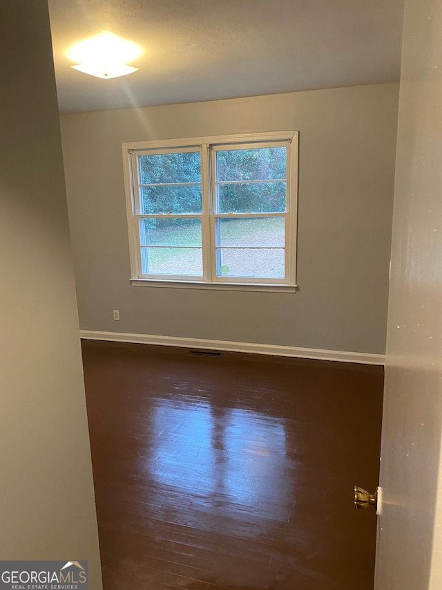 unfurnished room featuring a wealth of natural light and dark hardwood / wood-style floors