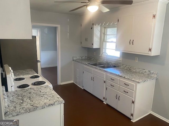 kitchen with sink, electric range, stainless steel refrigerator, and white cabinetry