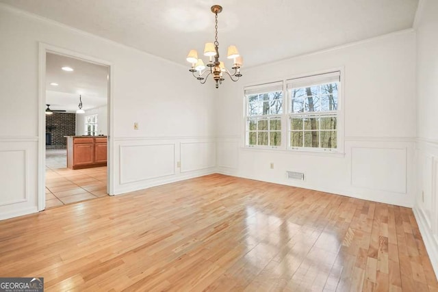 unfurnished dining area featuring ornamental molding, light hardwood / wood-style floors, and ceiling fan with notable chandelier