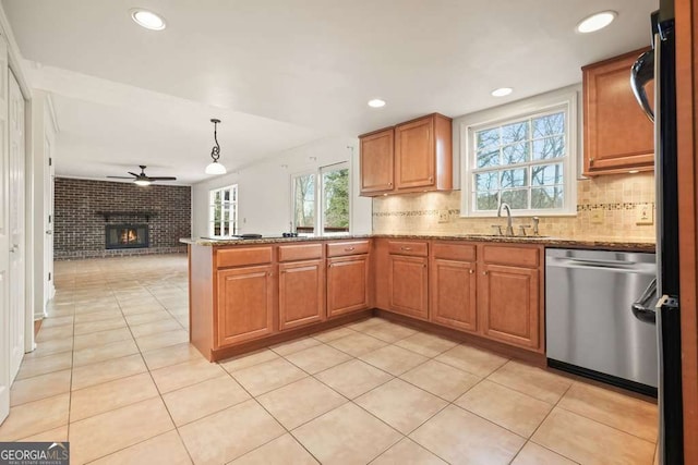 kitchen with stainless steel appliances, ceiling fan, a brick fireplace, backsplash, and hanging light fixtures