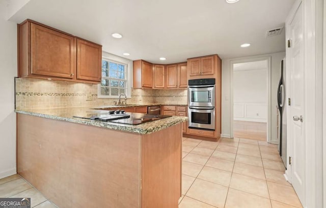 kitchen with sink, light tile patterned floors, kitchen peninsula, backsplash, and appliances with stainless steel finishes