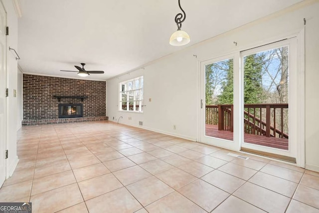 unfurnished living room with light tile patterned flooring, a brick fireplace, ceiling fan, and ornamental molding