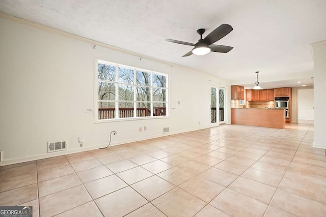 unfurnished living room with ceiling fan, crown molding, and light tile patterned floors