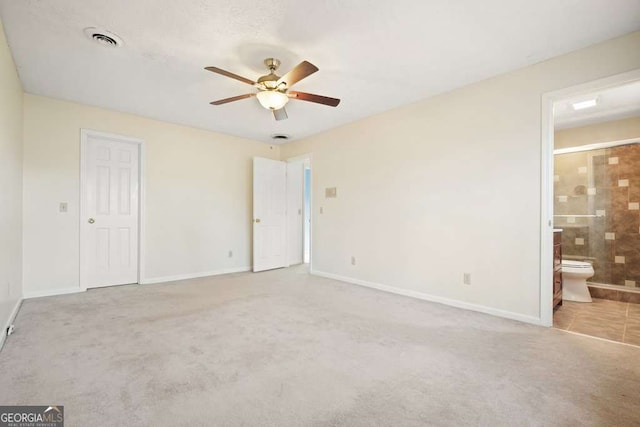 unfurnished bedroom featuring ensuite bath, light colored carpet, ceiling fan, and a closet