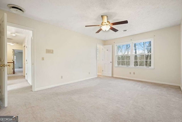 carpeted spare room featuring ceiling fan and a textured ceiling