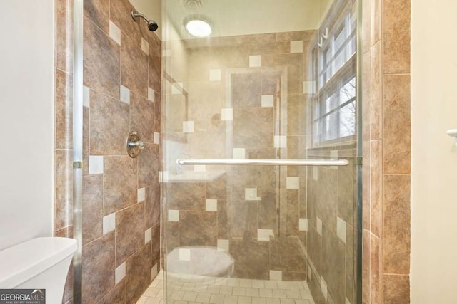 bathroom featuring toilet and a shower with door