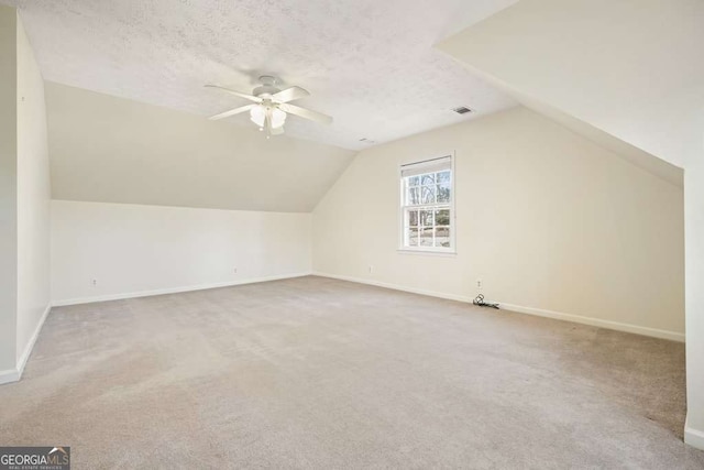 additional living space with a textured ceiling, ceiling fan, vaulted ceiling, and carpet floors