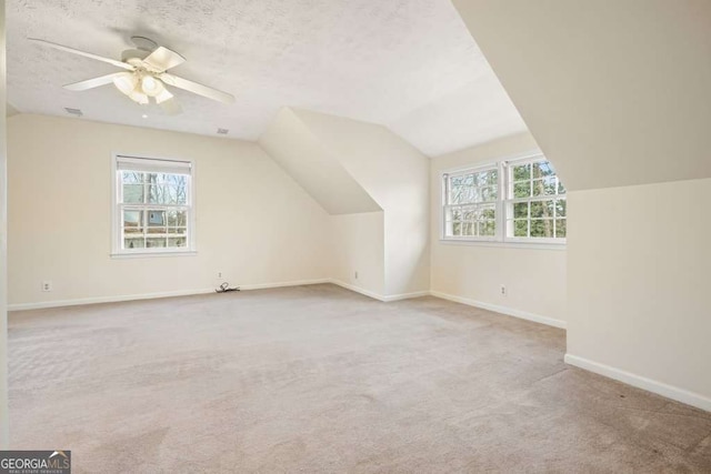 bonus room featuring a textured ceiling, light carpet, and ceiling fan