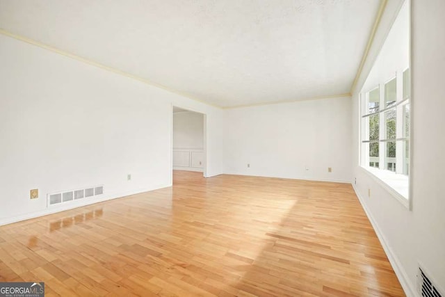 spare room featuring light hardwood / wood-style flooring and crown molding