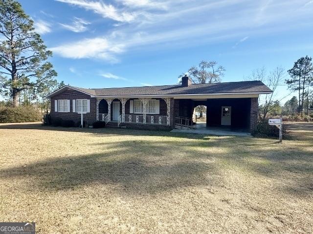 ranch-style house with covered porch and a front lawn