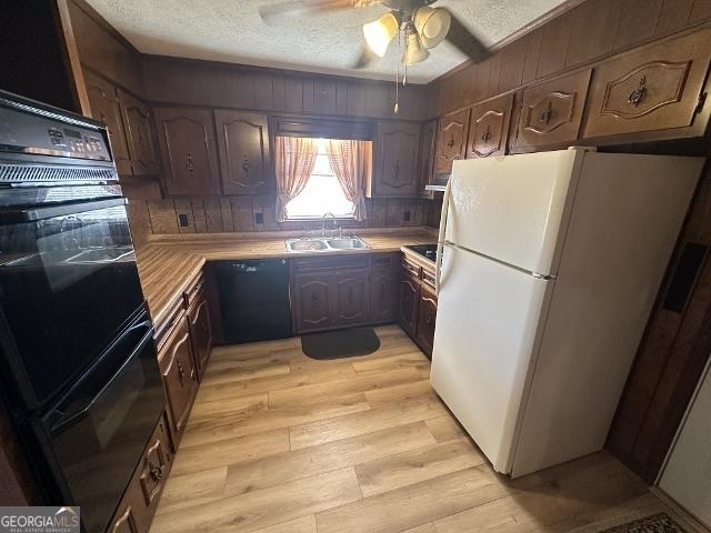 kitchen with black appliances, ceiling fan, a textured ceiling, sink, and light hardwood / wood-style flooring