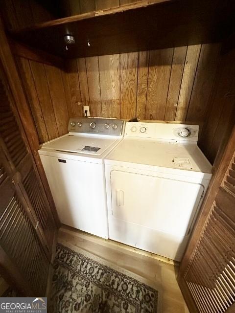 clothes washing area featuring washer and dryer and wooden walls