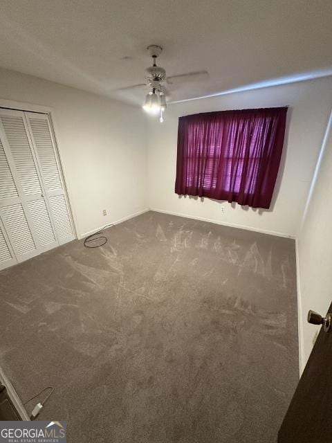 unfurnished bedroom with a closet, ceiling fan, and dark colored carpet