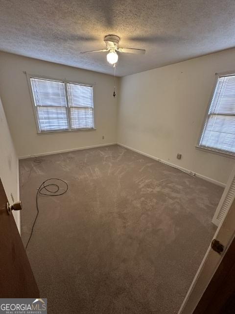 spare room with a textured ceiling, ceiling fan, and carpet flooring