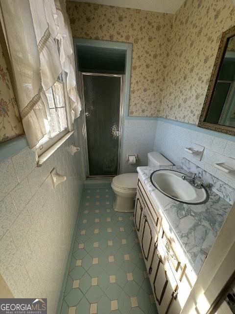 bathroom with a shower with door, tile patterned floors, vanity, and toilet