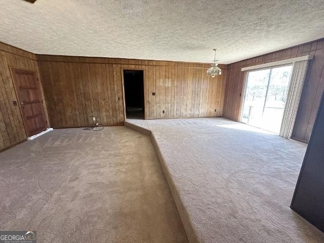 unfurnished room featuring carpet floors and wooden walls