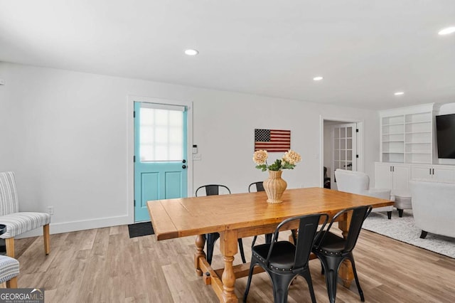 dining room with built in shelves and light hardwood / wood-style flooring