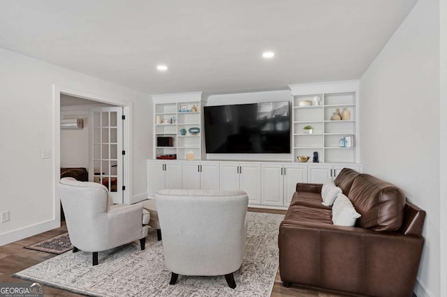 living room with wood-type flooring, a wall unit AC, and french doors