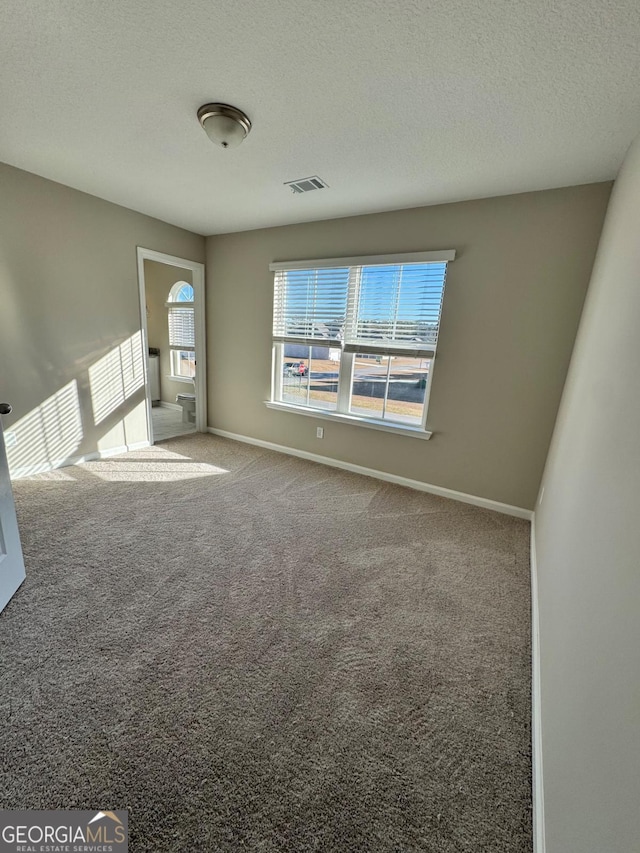 carpeted empty room featuring a textured ceiling