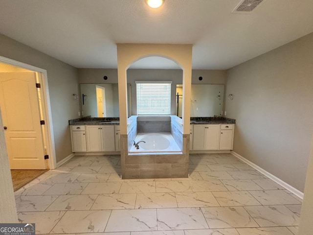 bathroom featuring vanity and tiled bath