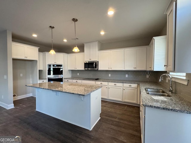 kitchen with stainless steel appliances, a kitchen island, white cabinetry, and sink