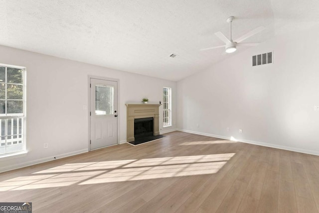 unfurnished living room with ceiling fan, light wood-type flooring, lofted ceiling, and a textured ceiling