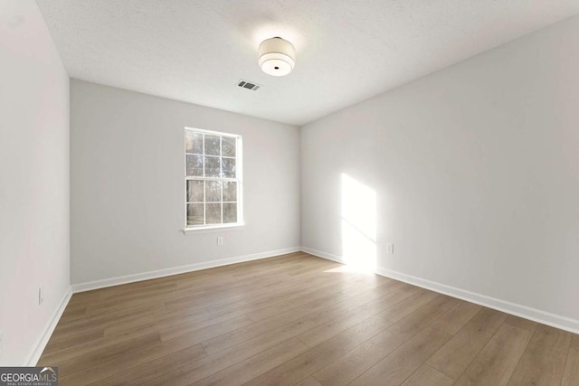 empty room featuring hardwood / wood-style flooring and a textured ceiling