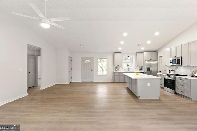 kitchen featuring gray cabinets, appliances with stainless steel finishes, ceiling fan, a kitchen island, and lofted ceiling