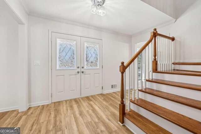 foyer with light hardwood / wood-style floors, crown molding, and plenty of natural light