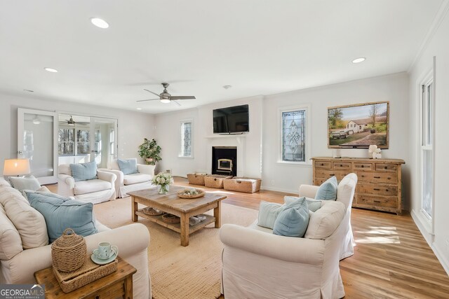 unfurnished living room with french doors, a tiled fireplace, light wood-type flooring, and plenty of natural light