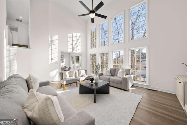 living room with a high ceiling, hardwood / wood-style floors, and ceiling fan