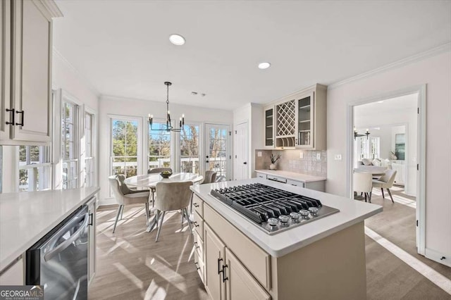 kitchen featuring pendant lighting, a kitchen island, an inviting chandelier, light wood-type flooring, and appliances with stainless steel finishes