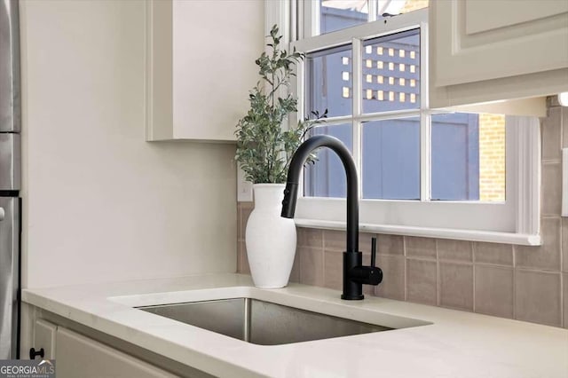 interior details featuring sink, white cabinets, and tasteful backsplash