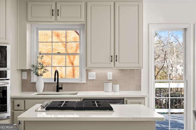 kitchen featuring stainless steel appliances, white cabinetry, backsplash, and sink