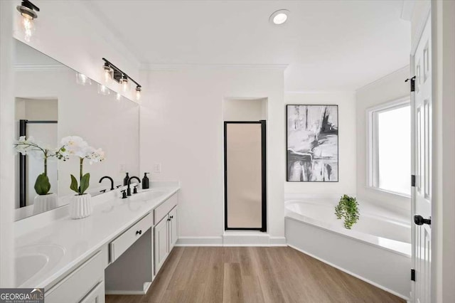 bathroom with independent shower and bath, vanity, ornamental molding, and hardwood / wood-style flooring