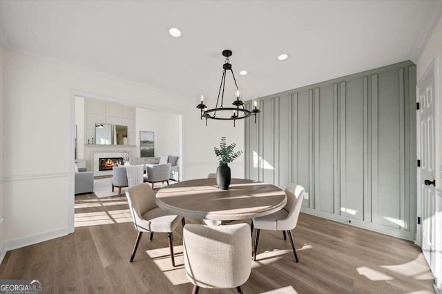 dining room with light wood-type flooring, an inviting chandelier, and crown molding