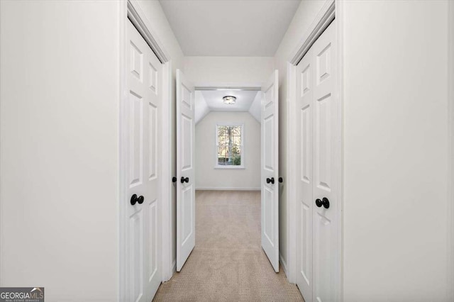 hallway with light colored carpet and lofted ceiling