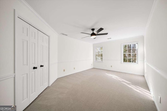 unfurnished bedroom featuring a closet, ceiling fan, carpet, and crown molding