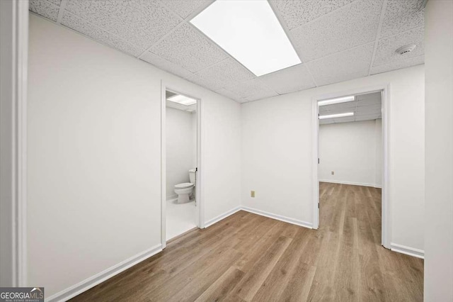 basement featuring a drop ceiling and light hardwood / wood-style floors